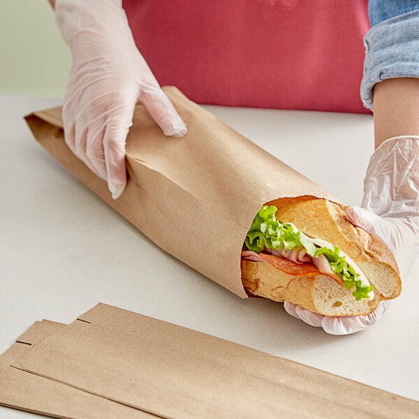 a hand in a glove holding a brown bag