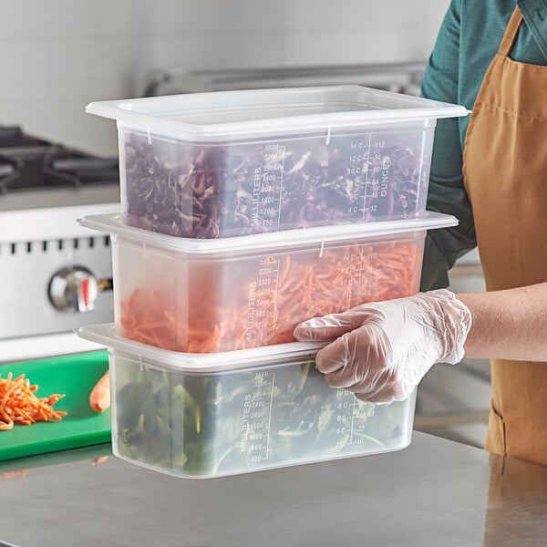 A woman holding a San Jamar translucent polypropylene food pan filled with vegetables.