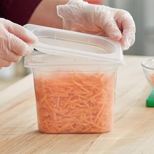 A gloved hand filling a San Jamar ModPan plastic container with carrots.