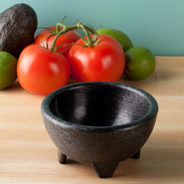 A black HS Inc. Polypropylene Molcajete on a table next to tomatoes and avocado.