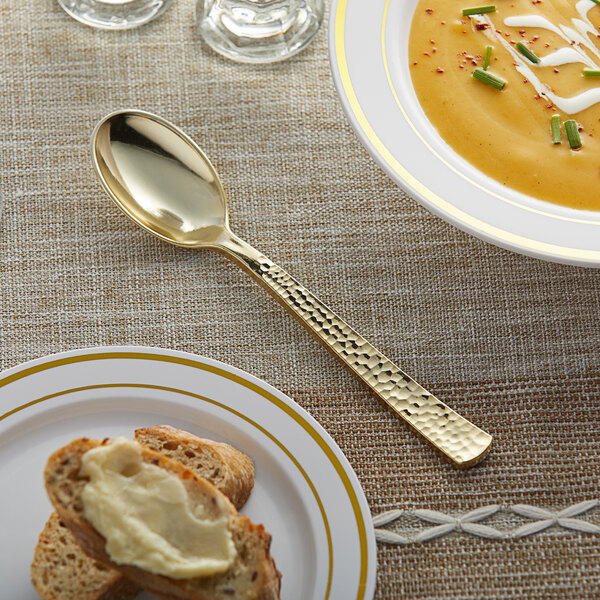 A Visions gold plastic spoon on a plate of soup.