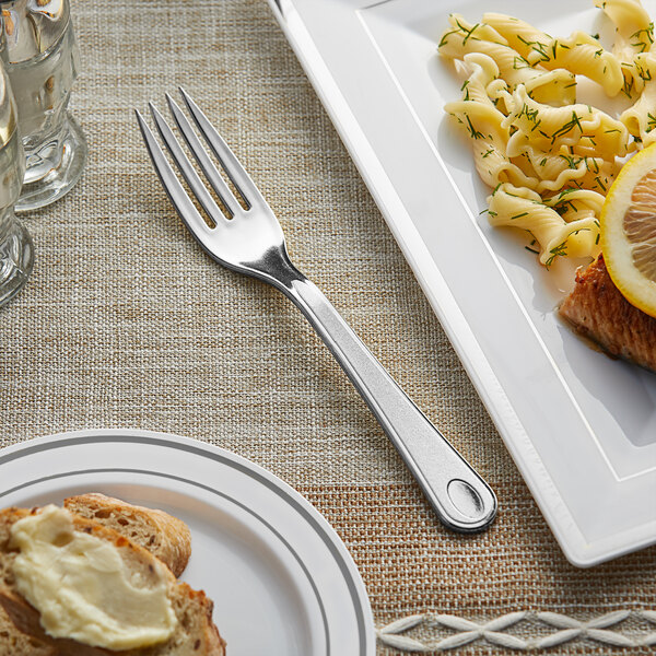 A Visions plastic fork on a table with a plate of food.