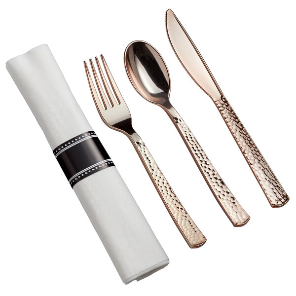 A Visions Hammersmith rose gold plastic cutlery set with a fork and spoon wrapped in a white napkin.