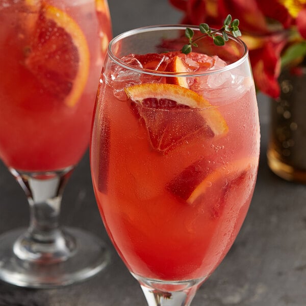 Two glasses of red liquid with Les Vergers Boiron Blood Orange garnish.