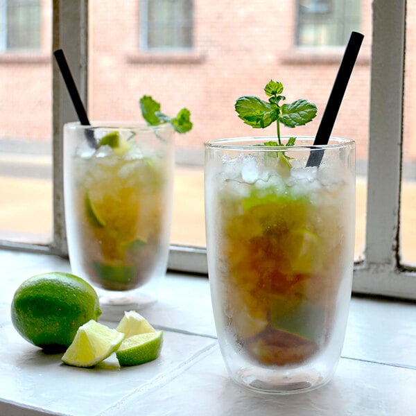 Two Villeroy & Boch double wall glass cups with a drink and lime wedges on the side.