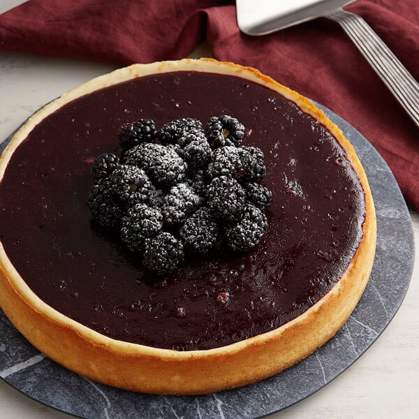 A slice of Les Vergers Boiron blackberry cheesecake with blackberries on top.