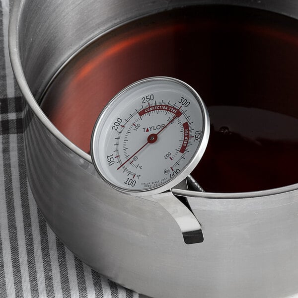 A Taylor 5911N Candy / Deep Fry Probe Thermometer in a pot of liquid.