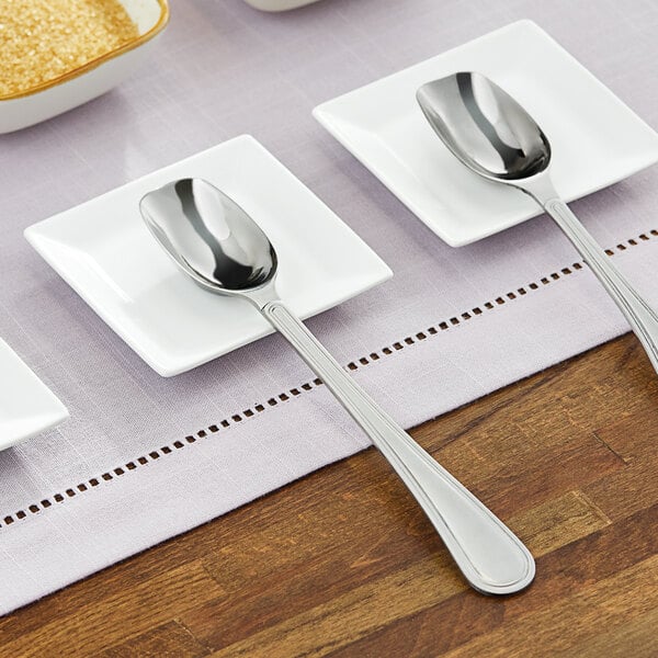 A group of white plates with stainless steel scoop spoons on them.