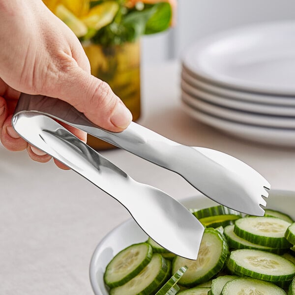 A person using GET Stainless Steel Salad Tongs to serve cucumber slices.