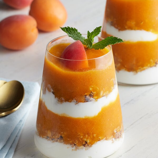 A glass of yogurt topped with apricot fruit puree and mint.