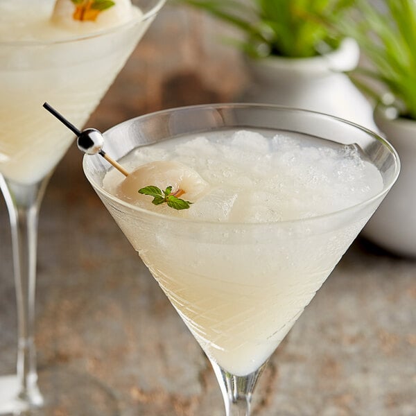 A close-up of two martini glasses filled with Les Vergers Boiron Lychee fruit puree over ice.