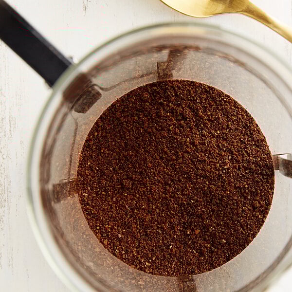 A glass container of Crown Beverages Royal Reserve Guatemalan Coarse Ground Coffee with a spoon in it.