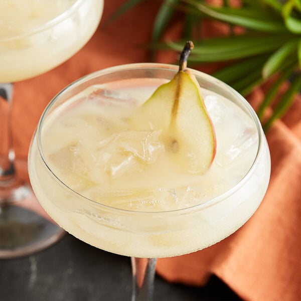 A glass of Les Vergers Boiron pear puree with ice and a pear slice.