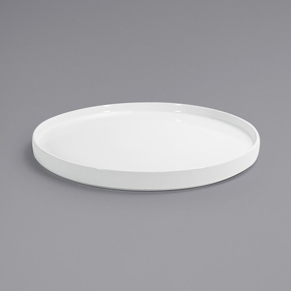 A Front of the House bright white porcelain plate with a raised rim on a gray surface.