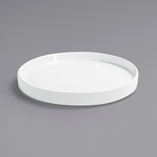 A Front of the House Soho bright white porcelain plate with a raised rim on a gray surface.