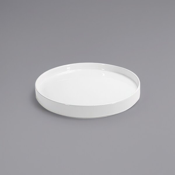 A Front of the House Soho bright white porcelain plate with a raised rim on a gray surface.