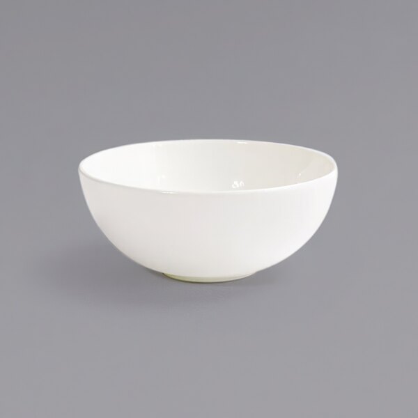 A Front of the House Catalyst European White coupe porcelain bowl on a gray surface.