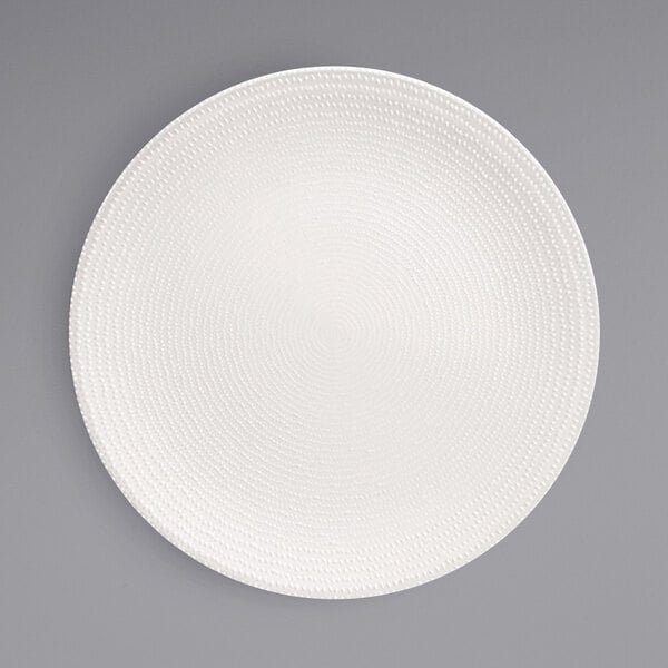 A Front of the House European white porcelain plate with a spiral pattern on the edge.