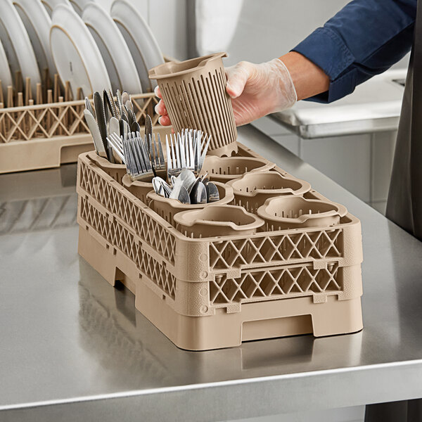A person putting utensils in a beige Vollrath Traex flatware rack.