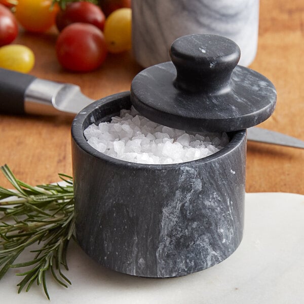 A Fox Run black marble salt cellar with salt inside on a kitchen counter.