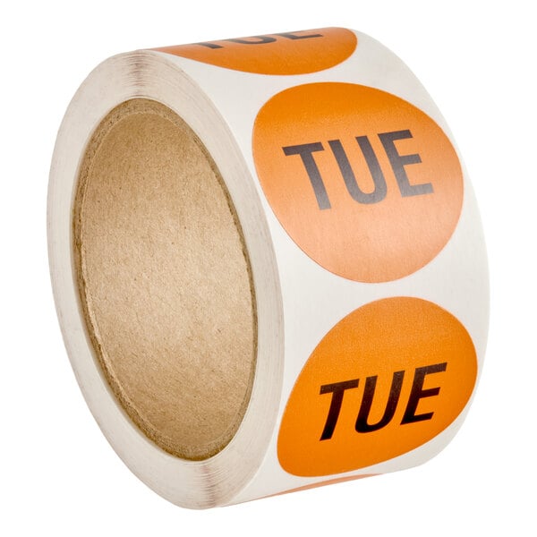 A roll of round orange labels with the word 'TUE' printed in black on each label.