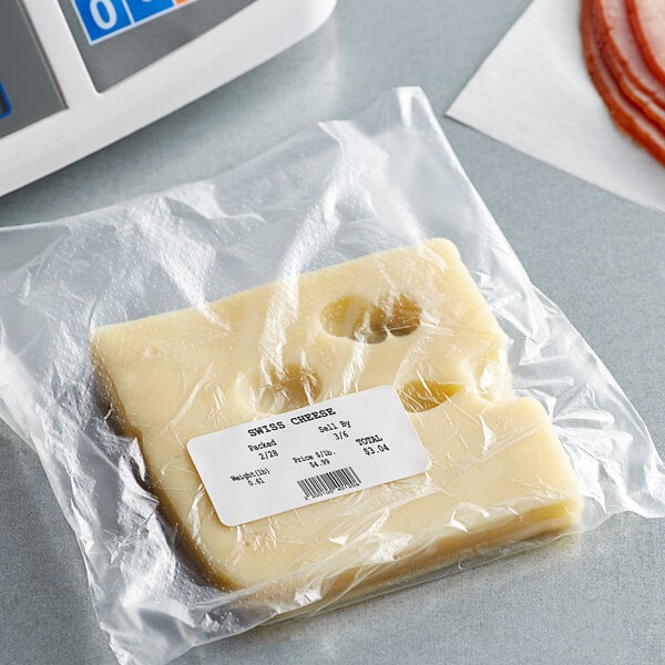 A piece of Cardinal Detecto white blank equivalent permanent direct thermal label on a plastic-wrapped piece of cheese next to a scale.