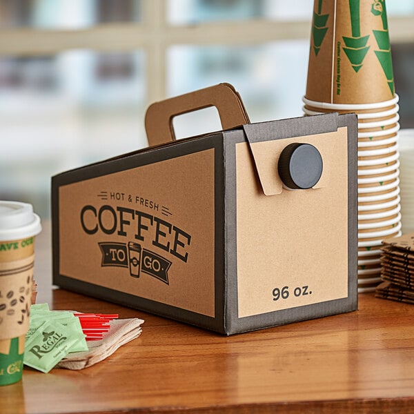 Coffee to-go box on a table with napkins, stirrers, sugar packets, and coffee cups