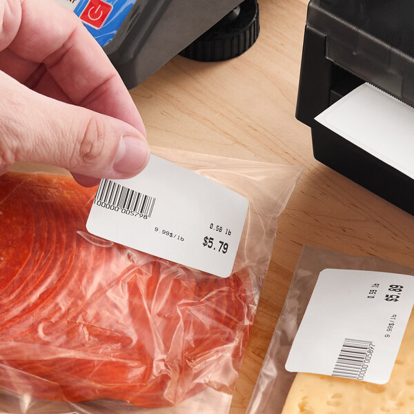 A roll of white blank permanent direct thermal labels being applied to packaged food products.