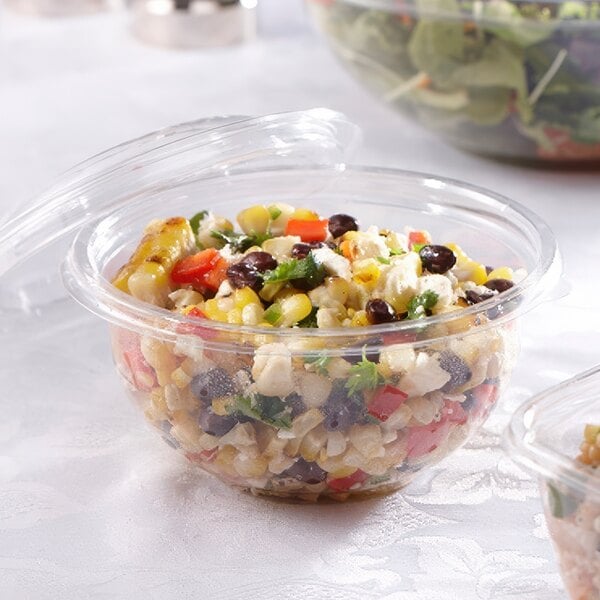 Two Sabert plastic containers filled with salad on a table.