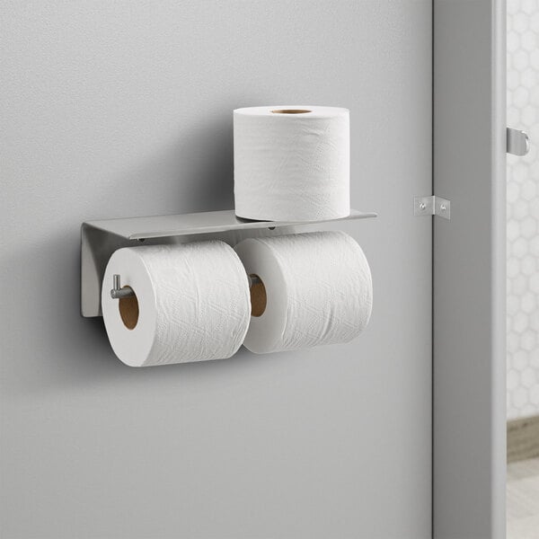 A white Bobrick surface-mounted multi roll toilet paper dispenser holding two rolls of toilet paper.