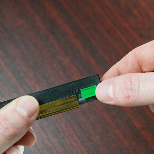 A person holding a black and green Unger ErgoTec squeegee blade.