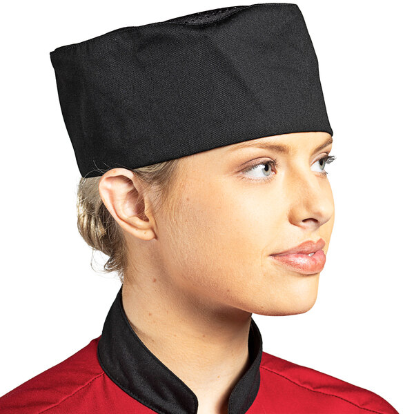 A woman wearing a black Uncommon Chef skull cap on a professional kitchen counter.