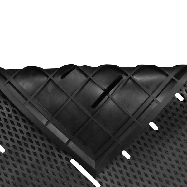A close up of a black rubber Guardian Free Flow utility floor mat with holes in it.