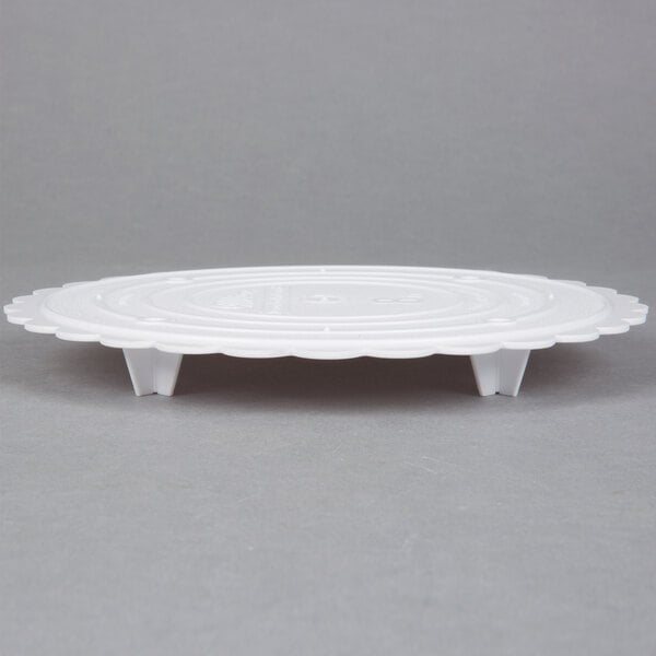 A white plastic Wilton cake separator plate with a scalloped edge.