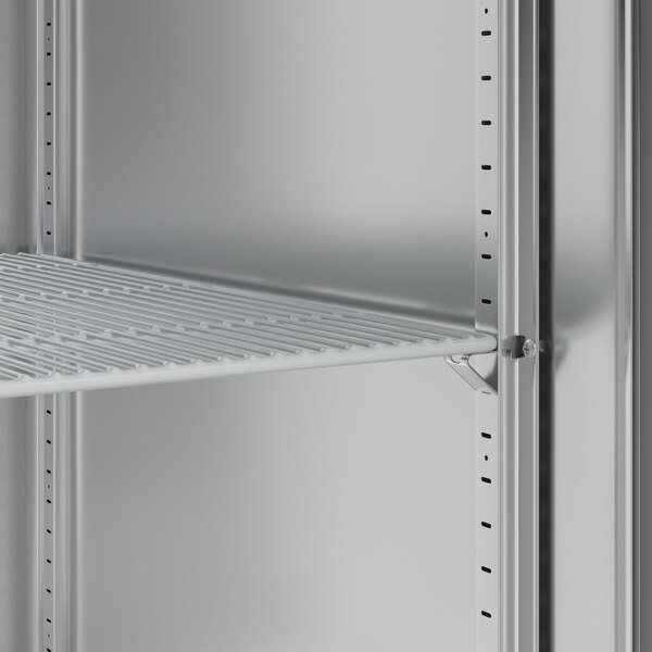 A metal shelf with holes inside a Hoshizaki reach-in freezer.