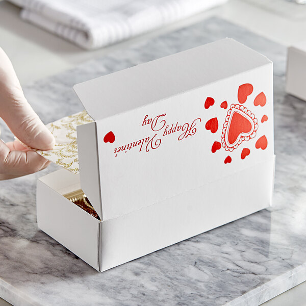 A hand putting a Valentine's Day candy box into a larger box.