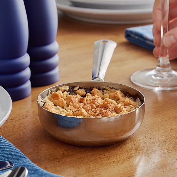 A Vollrath mini stainless steel fry pan with food on a table.