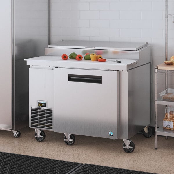 A stainless steel Hoshizaki commercial refrigerator with vegetables on top.