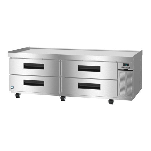 A stainless steel refrigerated chef base with four drawers and caster wheels.