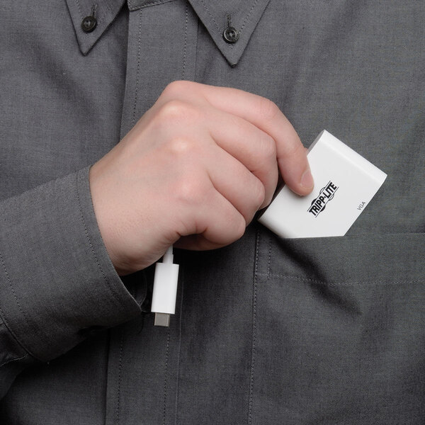 A hand holding a small white Tripp Lite USB-C to VGA adapter in a pocket.