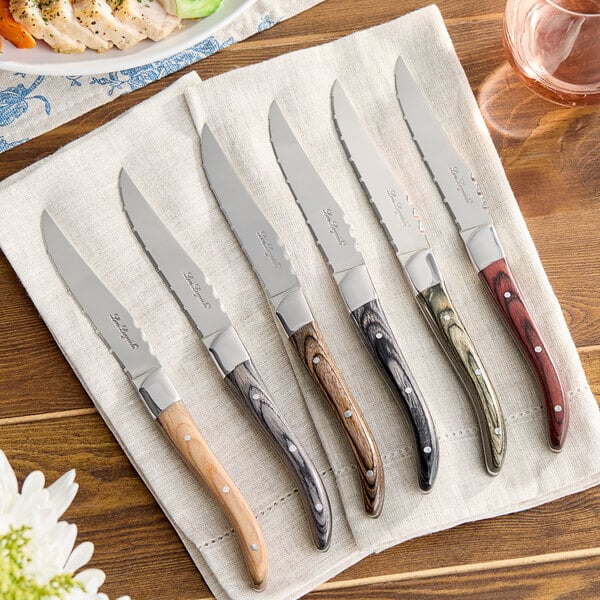 A group of Lou Laguiole steak knives with wooden handles on a table.
