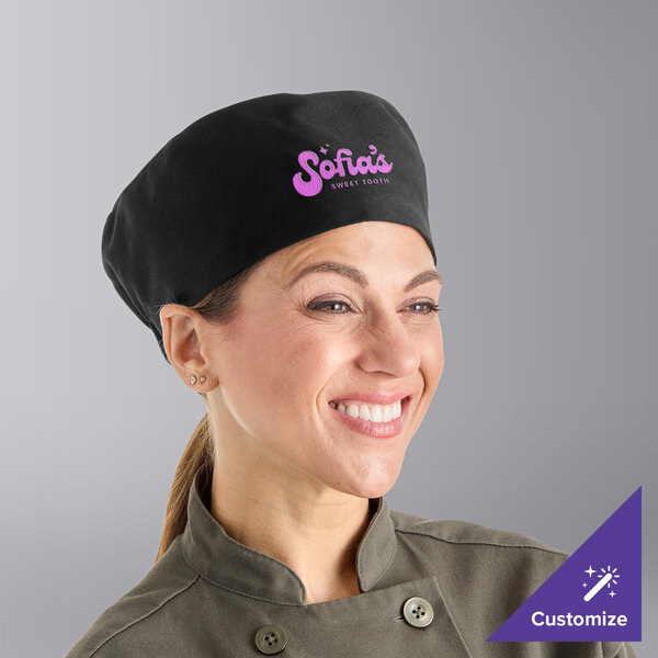 A smiling woman wearing a black Uncommon Chef skull cap in a professional kitchen.