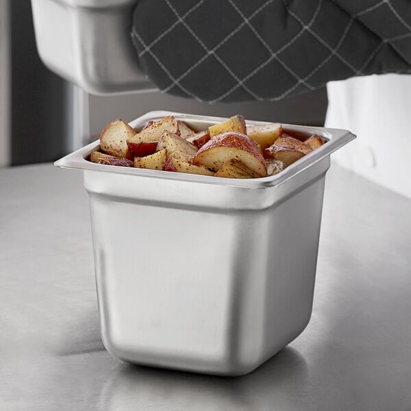 A person holding a Carlisle stainless steel steam table pan of potatoes.