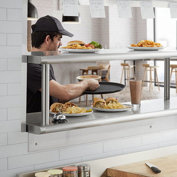 A man serving food from a counter with Regency pass-through shelving above.