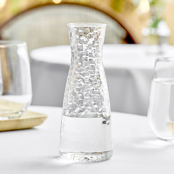 A Front of the House Drinkwise clear plastic carafe filled with a clear liquid on a table