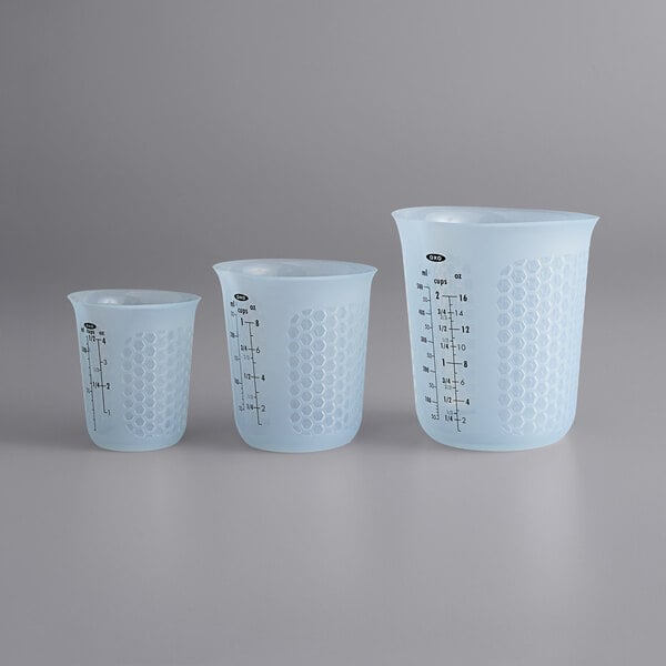 A group of three OXO Good Grips translucent silicone measuring cups with different sizes.