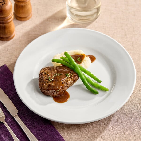 A Oneida Buffalo Bright White Ware porcelain plate with meat and green beans on it.