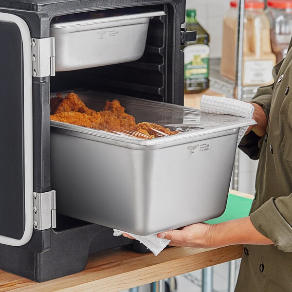 A woman holding a Vollrath stainless steel tray of food.