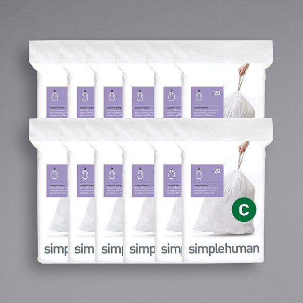 A person holding a white package of simplehuman trash can liners.