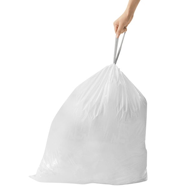 A person holding a white simplehuman trash bag.